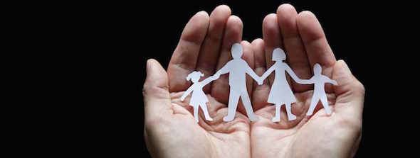 hand holding family figure paper cut out