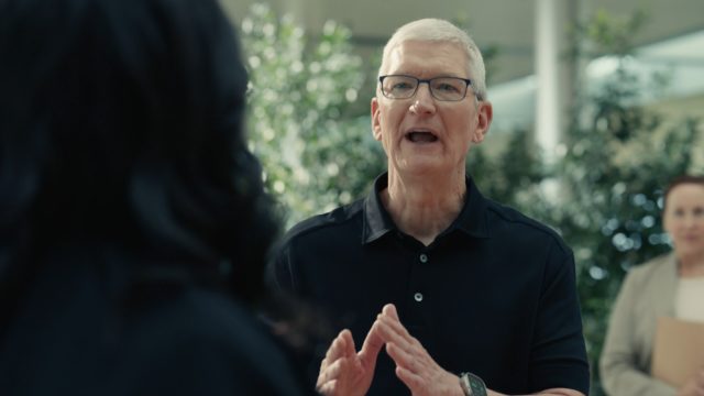 From iPhoneIslam.com, Tim Cook discusses the iPhone 15 with a woman in an office.