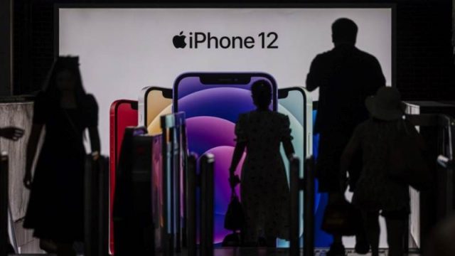 Depuis iPhoneIslam.com, un groupe de personnes passe devant un écran d'iPhone 12, alors que le régulateur français suspend les ventes en raison de niveaux de rayonnement élevés.