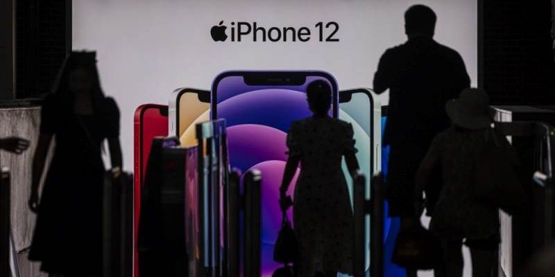 Depuis iPhoneIslam.com, un groupe de personnes passe devant un écran d'iPhone 12, alors que le régulateur français suspend les ventes en raison de niveaux de rayonnement élevés.