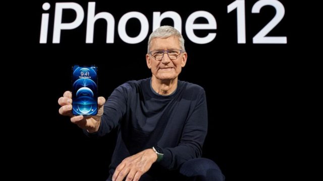 Από το iPhoneIslam.com, Περιγραφή: Ο Τιμ Κουκ ποζάρει με το iPhone 12 μπροστά από το λογότυπο της Apple. τις κύριες λέξεις