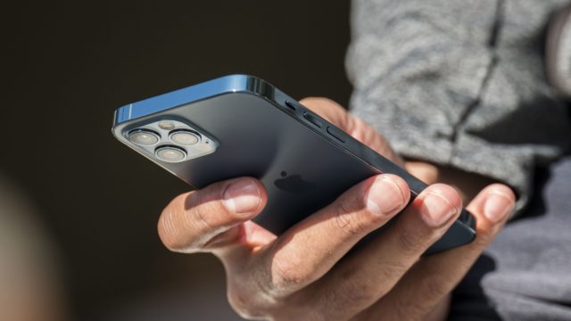 من iPhoneIslam.com، شخص يحمل جهاز iPhone ويعرض ميزة جديدة لتعزيز الأمان.