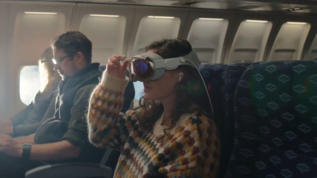 از iPhoneIslam.com، زنی با هدست واقعیت مجازی در هواپیما، دنیای مجازی همهجانبه ژانویه را تجربه می کند.