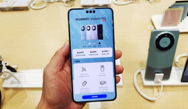 iPhoneislam.com से, एक व्यक्ति एक स्टोर में Huawei फोन रखता है।