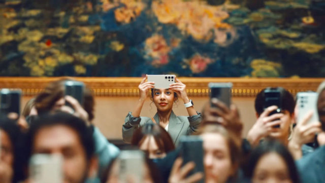 Da iPhoneIslam.com, un gruppo di persone che si scattano selfie davanti a un dipinto artistico durante il lancio della serie Galaxy S24.