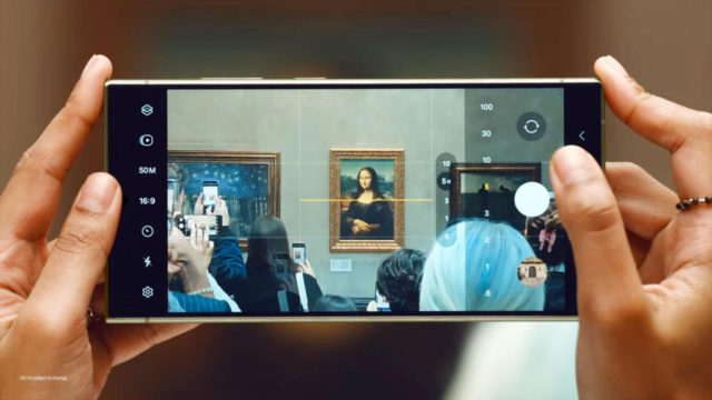 از iPhoneIslam.com، شخصی از گوشی هوشمند سری Galaxy S24 برای گرفتن عکس از یک نقاشی هنری استفاده می کند.