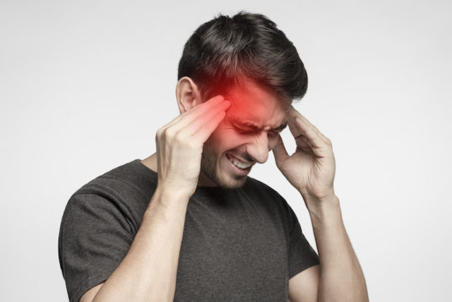 iPhoneislam.com से, सिरदर्द से पीड़ित एक व्यक्ति, एप्पल ग्लास पहने हुए, अपने हाथों को अपने सिर के ऊपर रखता है।