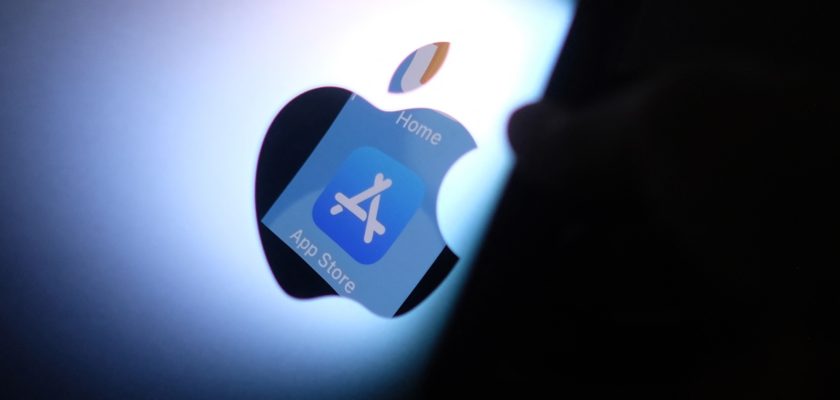 From iPhoneIslam.com, a person holds the Apple logo in front of the screen after Apple was fined.