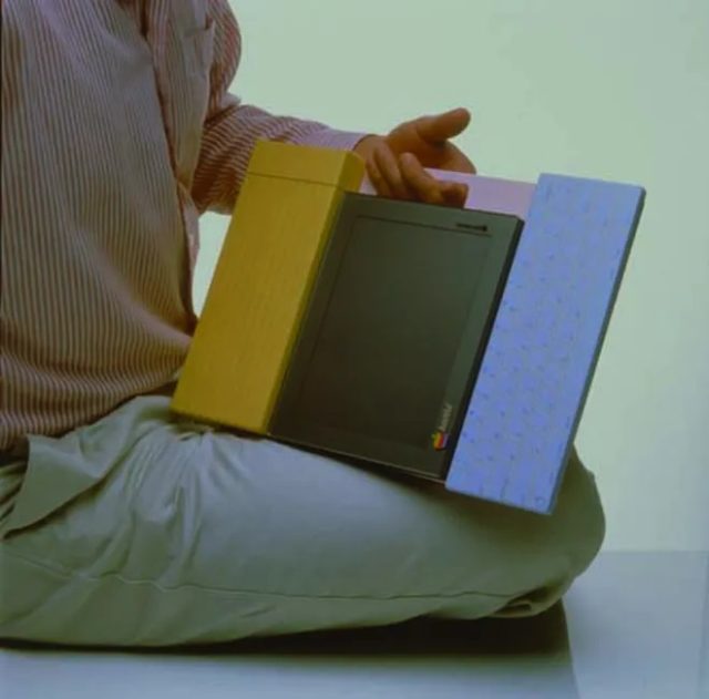 من iPhoneIslam.com، شخص يجلس القرفصاء ويحمل جهاز كمبيوتر محمولًا مفتوحًا، ويعمل على مشاريع طموحة.
