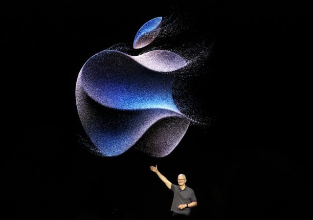 Desde iPhoneIslam.com, un hombre muestra un gran logotipo de Samsung iluminado hecho de partículas azules sobre un fondo oscuro en un evento.