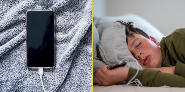 من iPhoneIslam.com، هاتف ذكي يشحن على بطانية رمادية، وصبي مراهق ينام وهو يحمل جهاز iPhone آخر.