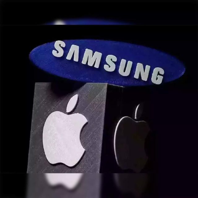 Z iPhoneIslam.com niebieskie logo Samsunga znajduje się nad dwoma logo Apple w skali szarości odbijającymi się na błyszczącej powierzchni.
