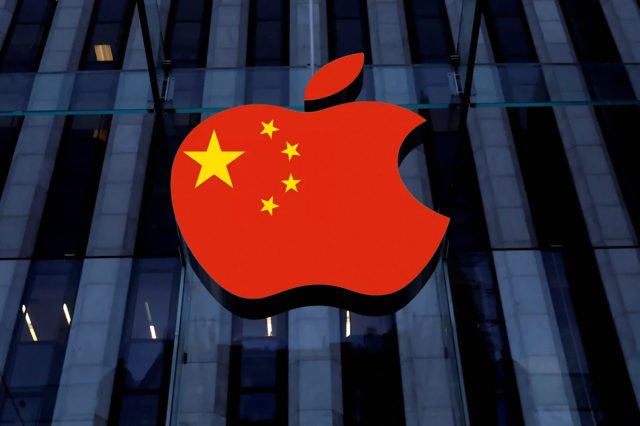 من iPhoneIslam.com، يمكن رؤية شعار Apple الذي يتميز بتصميم العلم الصيني المعروض على الواجهة الزجاجية للمبنى ليلاً من متجر التطبيقات.
