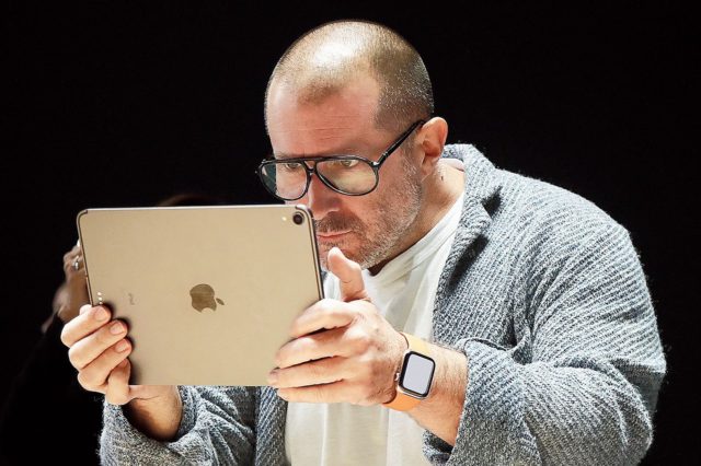 iPhoneIslam.com'dan gözlük ve akıllı saat takan odaklanmış bir kişi tableti yakından inceliyor.