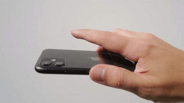 من iPhoneIslam.com، يد تحوم فوق هاتف آي فون أسود مزود بكاميرات مزدوجة، تستعد للمس الشاشة.