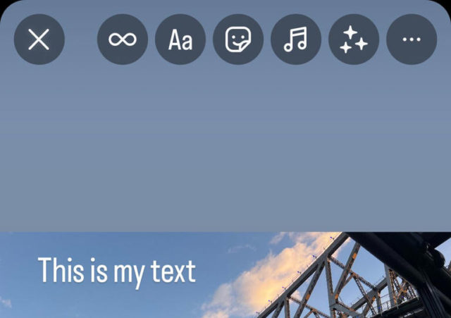 من iPhoneIslam.com، جسر مرئي جزئيًا مقابل سماء زرقاء مع بعض السحب. تشير أيقونات الواجهة في الجزء العلوي إلى وجود تطبيق تحرير قيد الاستخدام على الآي-فون، والنص "This is my نص" متراكب على الصورة.