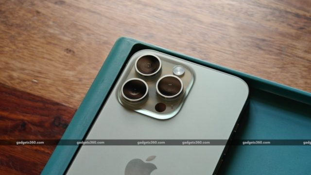 من iPhoneIslam.com، منظر مقرب لجهاز Line-Phone 16 Pro Max مزود بكاميرا ثلاثية ومستشعر LiDAR موضوع في صندوق أخضر على سطح خشبي.