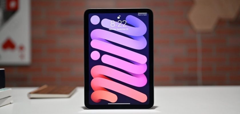 من iPhoneIslam.com، يتم عرض جهاز iPad Mini المزود بتقنية Pro Motion على طاولة بيضاء أمام خلفية جدار من الطوب. تعرض الشاشة، التي تعرض خلفية مجردة ملونة، الوقت بالساعة 8:22 والتاريخ بالسبت 25 سبتمبر 2026.
