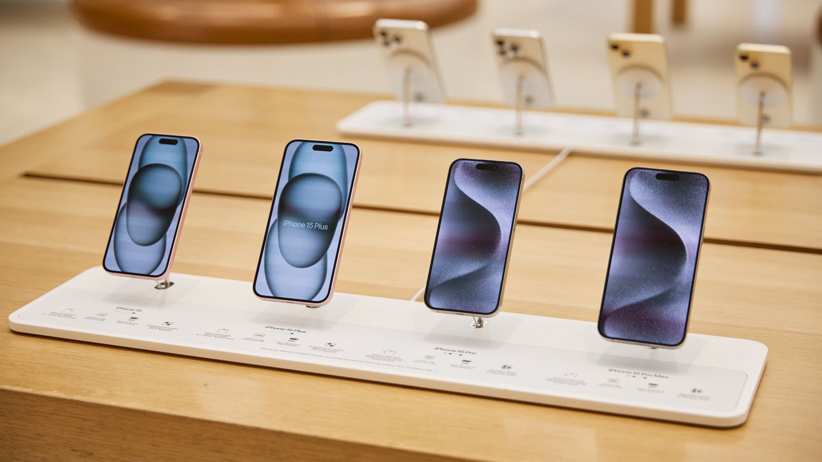 Desde iPhoneIslam.com, se muestran cinco teléfonos inteligentes en una tienda minorista, cada uno mostrando su pantalla con diferentes fondos de pantalla, incluidas las últimas actualizaciones de noticias.