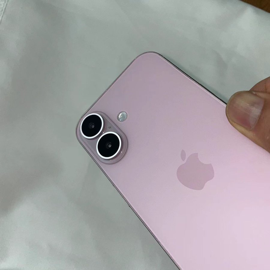 Da iPhoneIslam.com, Una mano tiene un iPhone viola con doppia fotocamera su uno sfondo chiaro a maggio.