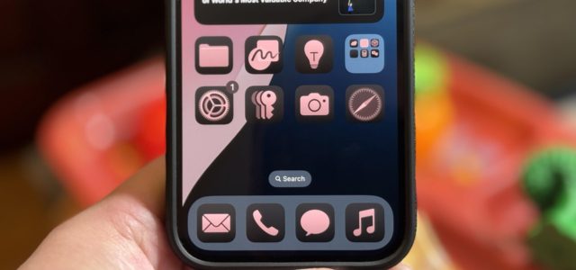 From iPhoneIslam.com, A person holds an iPhone with a black and pink home screen showing various app icons, including Music, Settings, Mail, and Messages. The screen displays a search bar and notifications badge on a single icon, highlighting the features of the iOS 18 update.