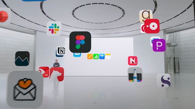 من iPhoneIslam.com، غرفة عرض حديثة وواسعة ذات سقف منحني. تطفو أيقونات التطبيقات المختلفة في المقدمة، بما في ذلك تطبيقات البريد الإلكتروني والإنتاجية والتصميم والمزيد. شخص يقف بالقرب من شاشة كبيرة.
