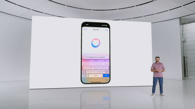 من iPhoneIslam.com، رجل يقف على خشبة المسرح ويعرض شاشة كبيرة تعرض هاتفًا ذكيًا به تطبيق مراسلة مفتوح.