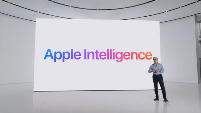 من iPhoneIslam.com، شخص يقف على خشبة المسرح بجوار شاشة كبيرة تعرض عبارة "Apple Intelligence" بنص ملون.