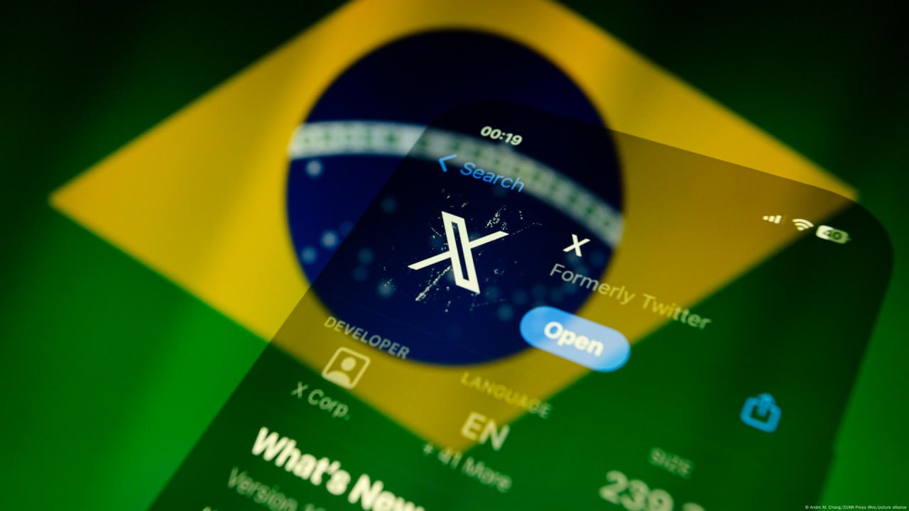من iPhoneIslam.com، تعرض شاشة الهاتف الذكي تطبيق X، المعروف سابقًا باسم Twitter، على خلفية ضبابية من العلم البرازيلي، وسط مناقشات حول تفكير البرازيل في حظر Ax.