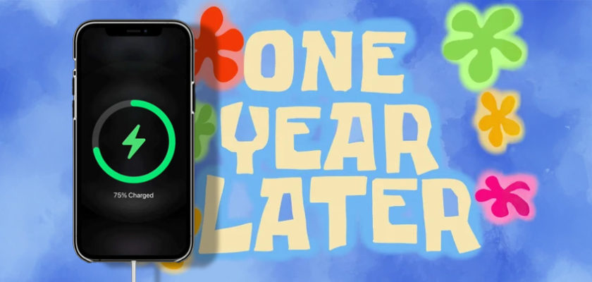 iPhoneIslam.com より、75% の充電を示すスマートフォン。背景に「One Year Later」の文字とカラフルな花の形が表示され、iPhone のバッテリー充電量が強調されています。