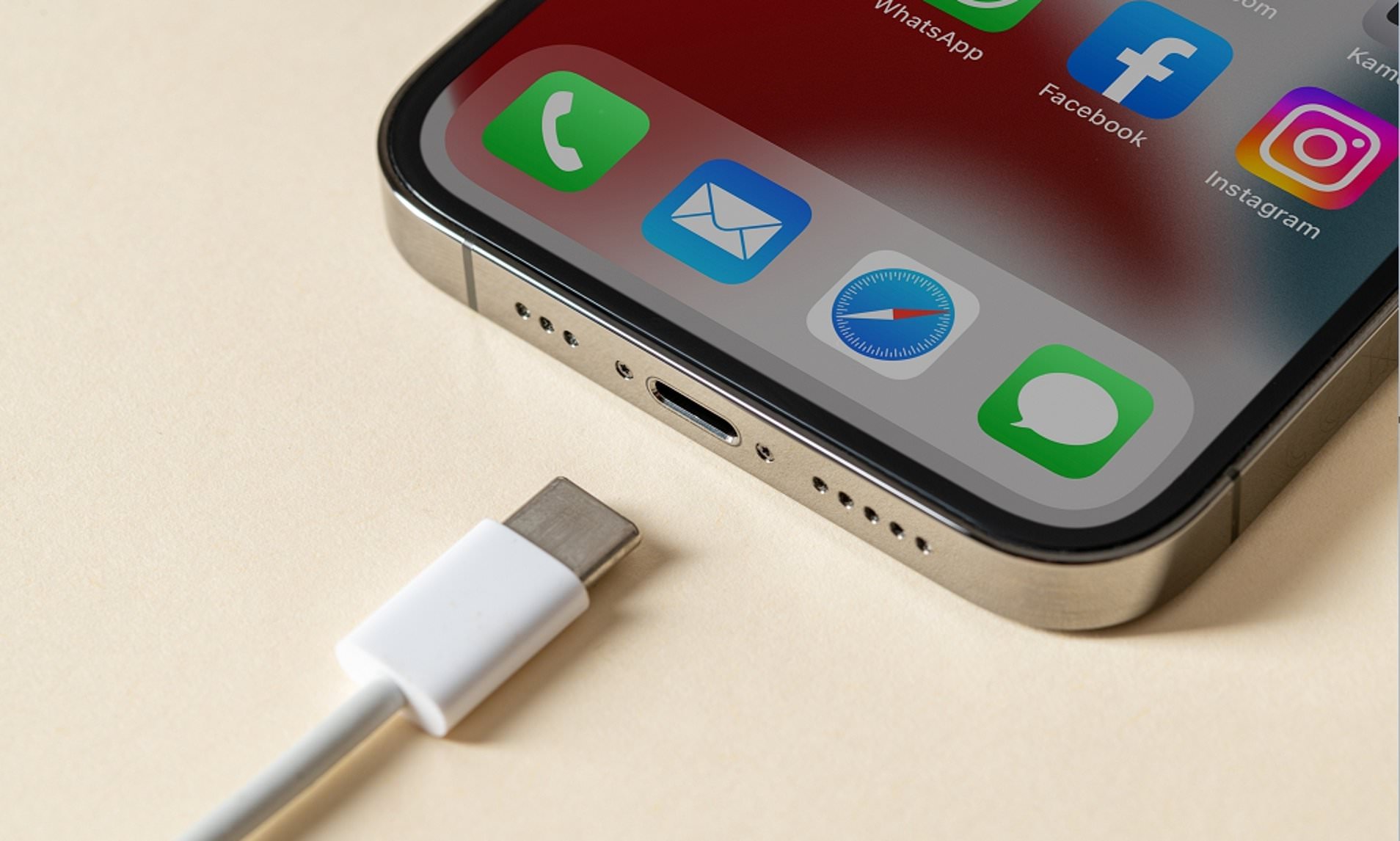 From iPhoneIslam.com, a close-up shot of a smartphone screen displaying app icons, with a charging cable near the charging port. The device is running iOS 18, providing multiple options and improved performance for the iPhone battery.