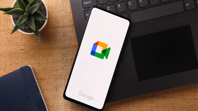 iPhoneIslam.com'dan Google Meet logolu bir akıllı telefon, lezzetli bir kasenin yanında bir dizüstü bilgisayar klavyesinin üzerinde duruyor ve bu, iPhone ile Android arasındaki kusursuz iletişimi geliştiren yeni özellikleri gösteriyor.