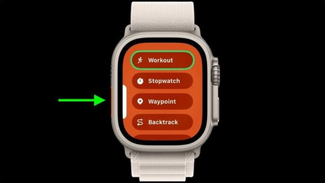 من iPhoneIslam.com، على خلفية سوداء أنيقة، تعرض الساعة الذكية خيارات مثل Workout وStopwatch وWaypoint وBacktrack. يسلط السهم الأخضر الضوء على ميزة التمرين. اكتشف الميزات الجديدة مع أحدث تحديثات الساعة الذكية لنظام التشغيل watchOS 11، مما يعزز كل جانب من جوانب رحلة اللياقة البدنية الخاصة بك.