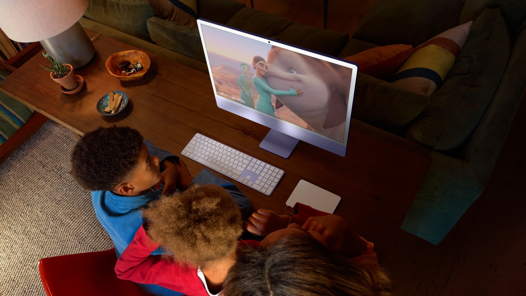 From Phonegram.com, three children sitting in front of an iMac with a nano-texture display, fascinated by vibrant animations of a character hugging an elephant.