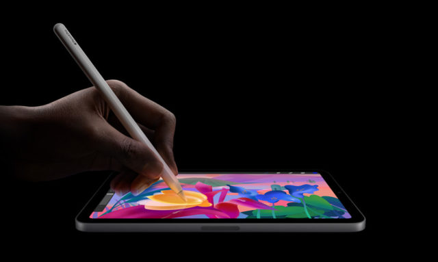 Depuis iPhoneIslam.com Une main utilise un stylet sur un iPad mini, affichant des dessins colorés sur fond noir, alimentés par l'intelligence avancée d'Apple.