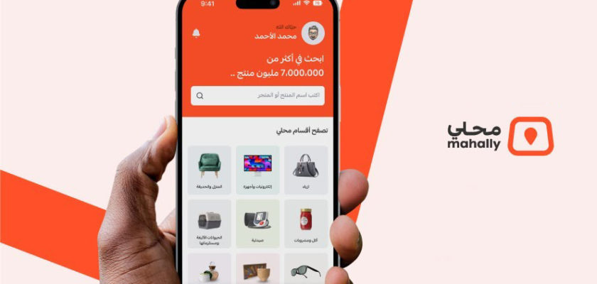 من iPhoneIslam.com، يد تحمل هاتفًا ذكيًا يعرض التطبيق المحلي باللغة العربية، ويعرض منتجات متنوعة. يظهر الشعار والنص "Mahally" على الجانب الأيمن، مما يربطك بسوق السعودية بسهولة.