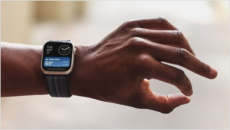 Da iPhoneIslam.com, si vede una persona che indossa un Apple Watch su cui sono visualizzati la data, l'ora e l'aggiornamento meteo mentre gesticola con una mano.