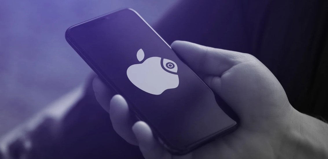 من iPhoneIslam.com، تحمل يد هاتفًا ذكيًا يحمل شعار شركة APPLE الأنيق: تفاحة مع عدسة كاميرا مدمجة بسلاسة في التصميم، مما يستحضر اندماجًا بين الابتكار والجماليات.