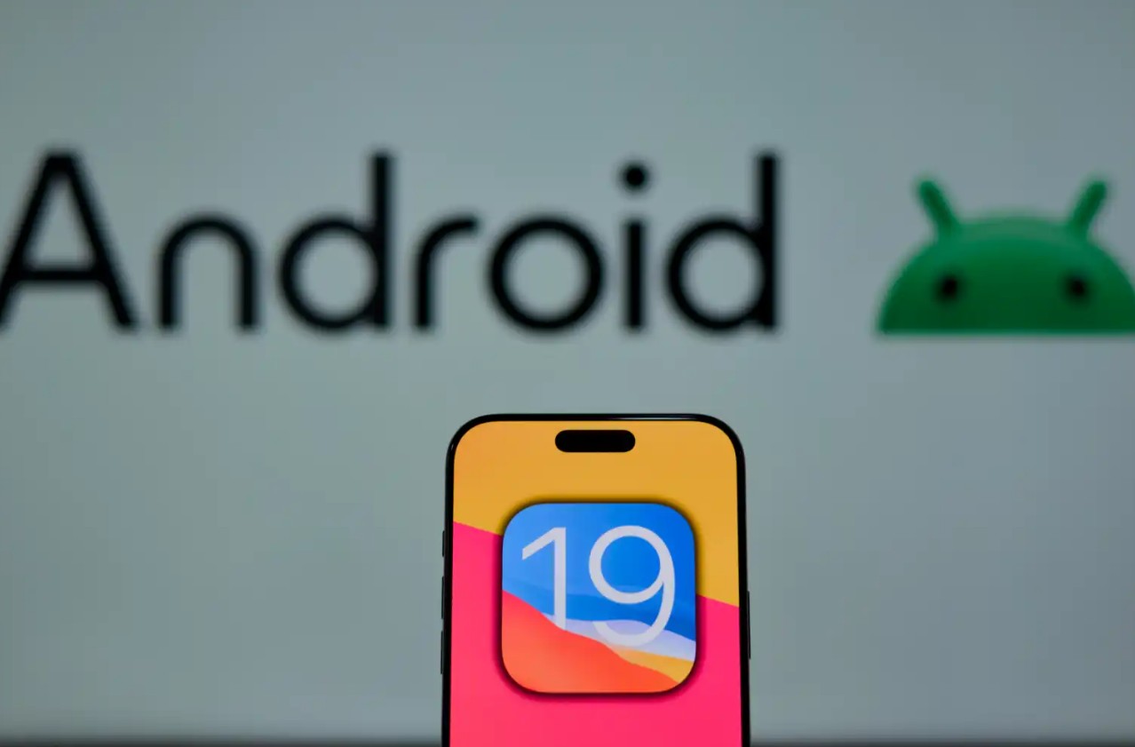 该图片来自 iPhoneIslam.com，显示一部智能手机上有一个数字 19 的图标，图标前面是一个模糊的 Android 14 标志，凸显了在持续的 Android 更新中人们对 iOS 19 的期待。
