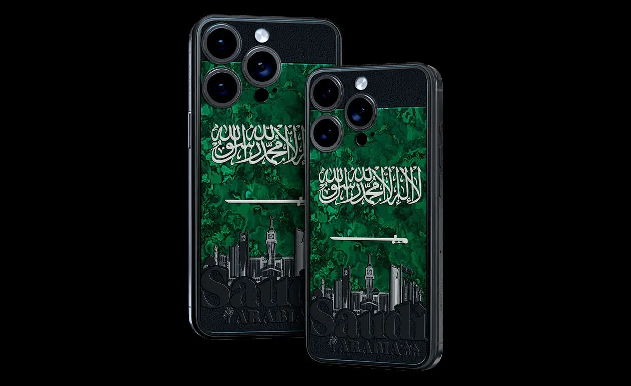 من iPhoneIslam.com، هاتفان ذكيان بحافظات من الرخام الأخضر تحمل علم المملكة العربية السعودية، ونص "المملكة العربية السعودية" فوق أفق مدينة أسود، وحقيقة أم خيال - حماية أنيقة مستوحاة من الآي فون، صنعت في السعودية.