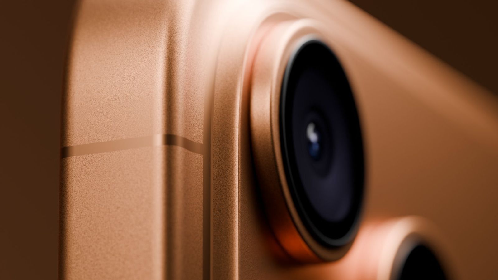 من iPhoneIslam.com، لقطة عن قرب لعدسة الكاميرا الخلفية وزاوية الهاتف الذكي الذهبي المعدني، تُظهر نسيج وتفاصيل وحدة كاميرا الجهاز وحافته.
