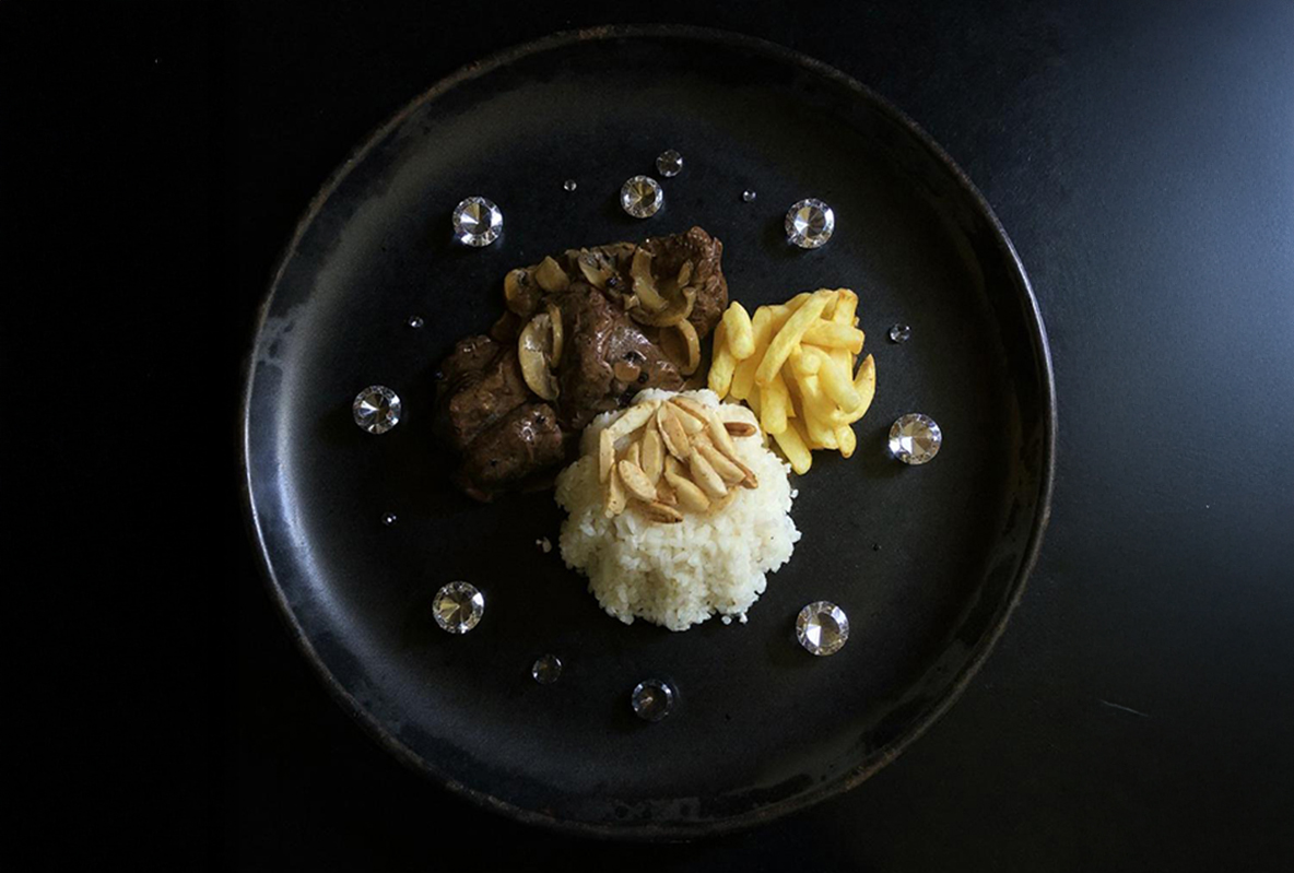 من iPhoneIslam.com، طبق أسود مع حصة من اللحم البقري والفطر والكسكسي المغطى باللوز المقطّع والمكرونة الصفراء، مقدمة بشكل جميل لصور الطعام أو شاركوها عبر تطبيق طعام جيني.