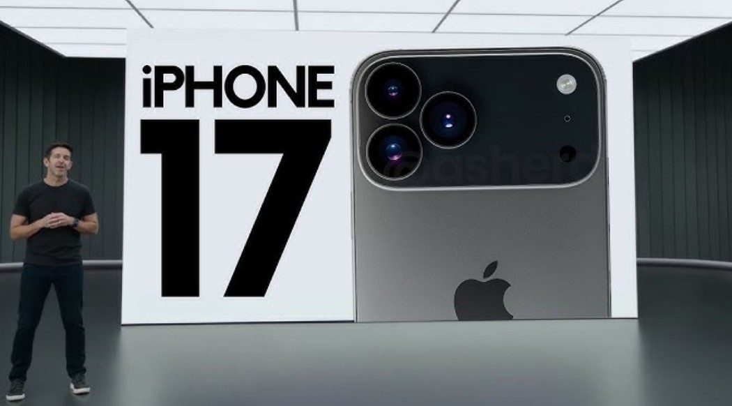 من iPhoneIslam.com، يقف أحد المقدمين بجانب شاشة عرض كبيرة في حدث آي فون 17، ويعرض اسم هاتف آيفون 17 إلى جانب صورة مقربة للكاميرا الخلفية وشعار أبل.