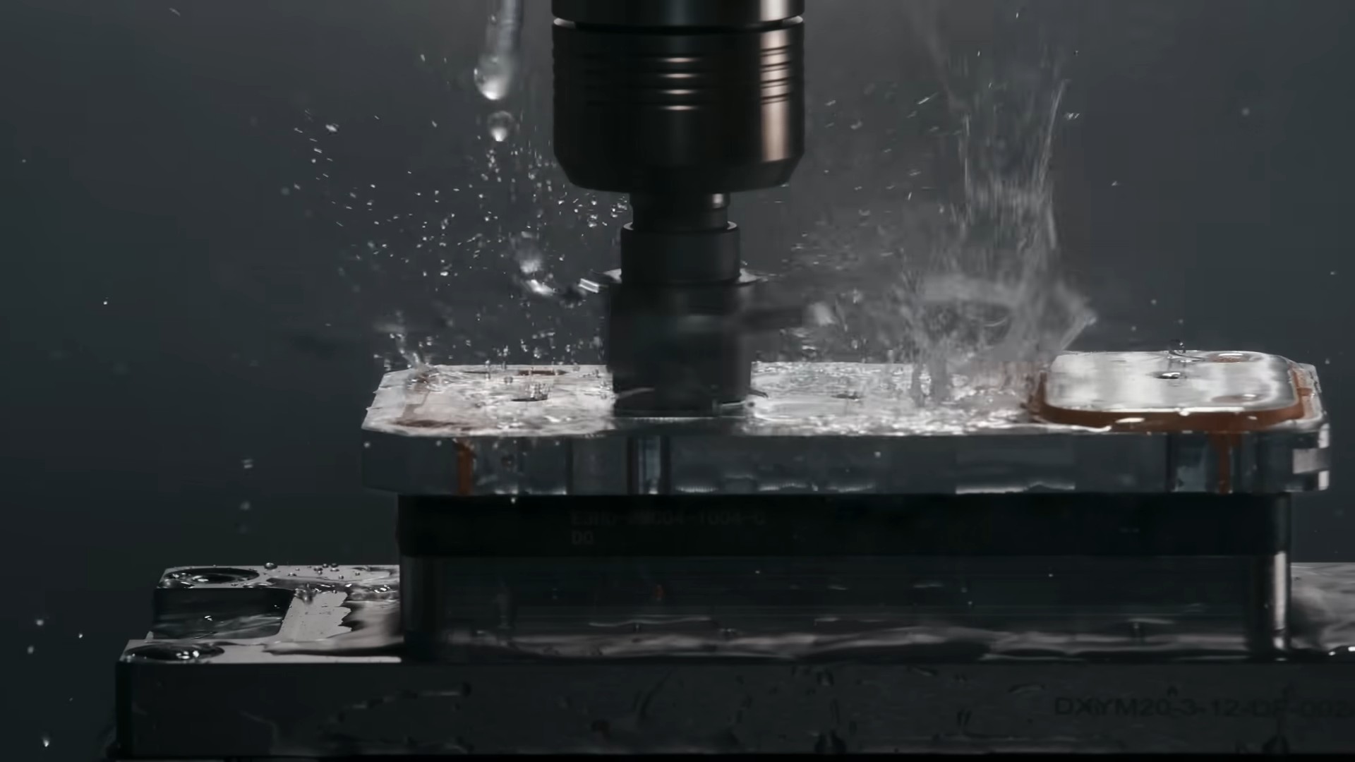 من موقع فون إسلام: صورة عن قرب لماكينة تفريز باستخدام الحاسب الآلي تقطع كتلة معدنية، مع تناثر سائل التبريد حول الأداة - الدقة في العمل تذكرنا بأجهزة التصنيع مثل آلة İ-فون إير.