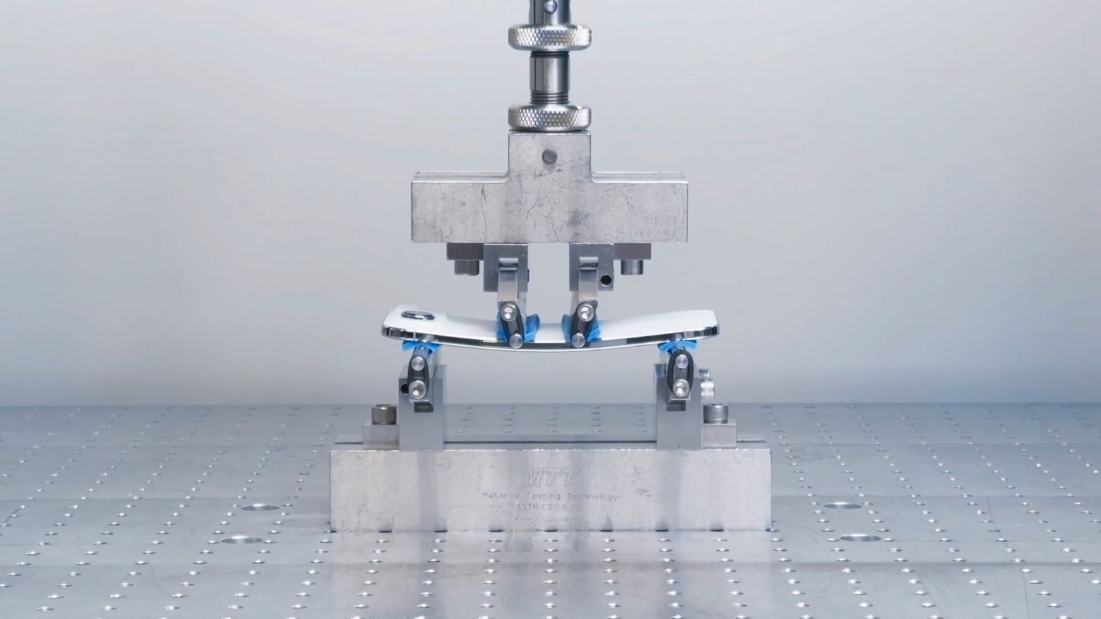 من موقع فون إسلام: آلة روبوتية تضغط على مركز الهاتف الذكي، وتختبر قوة ثنيه على منصة معدنية - وهو مثال على أخبار التقنية وراء متانة الجهاز.