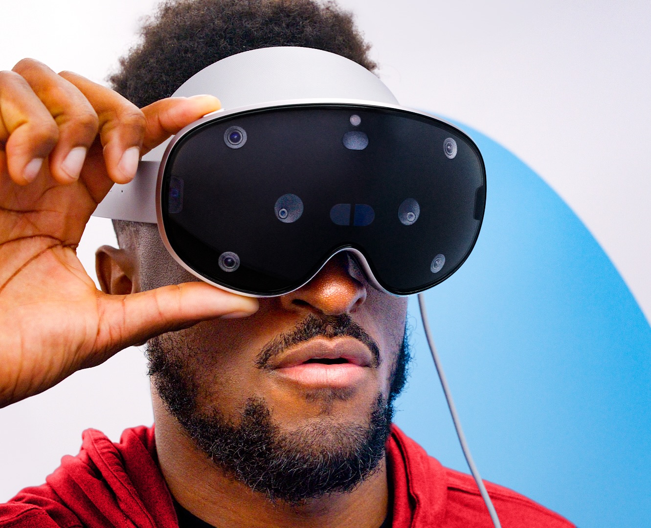 من موقع فون إسلام: شخص يرتدي سماعة سامسونج جلاكسي XR نظارة XR المزودة بمستشعرات متعددة، ويضبطها بيد واحدة.