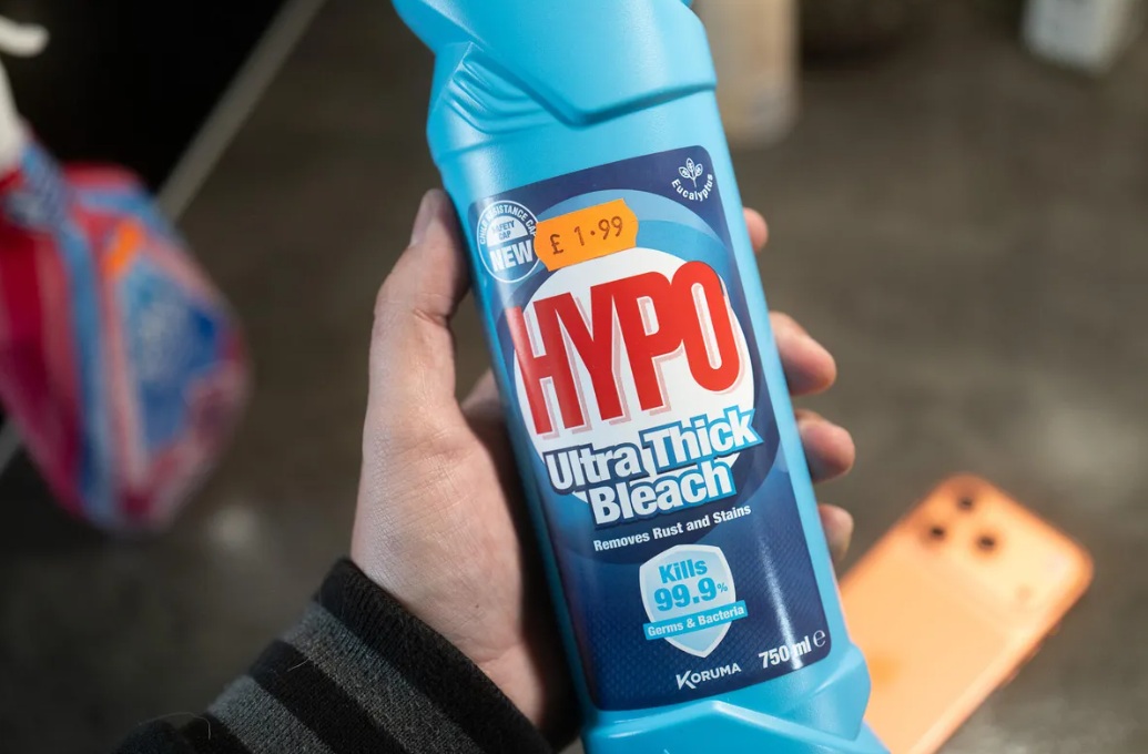 من موقع فون إسلام: يد تحمل زجاجة زرقاء سعة 750 مل من مبيض HYPO فائق السماكة بسعة 750 مل، وعليها ملصق بسعر 1.99 جنيه إسترليني على الملصق، وبجوارها برو برو البرتقالي 17.