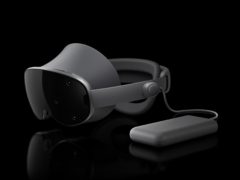 من موقع فون إسلام: أسود أنيق سامسونج جلاكسي جلاكسي XR نظارة افتراضي مع حزام رأس وجهاز خارجي مستطيل موصول، معروضة على خلفية سوداء.