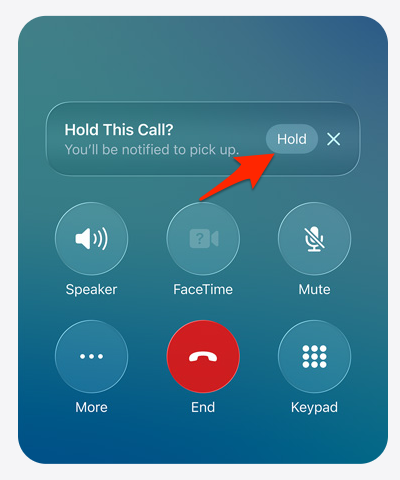 من موقع فون إسلام: شاشة مكالمات iPhone على نظام iOS 26 تظهر المطالبة "Hold This Call?" مع ميزة مساعد التعليق (Hold Assist) وسهم أحمر يشير إلى زر "Hold". تظهر خيارات مكبر الصوت، و FaceTime، وكتم الصوت، والمزيد، والإنهاء، ولوحة المفاتيح.