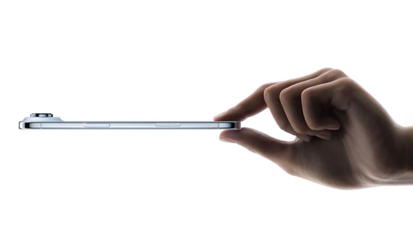 من موقع فون إسلام: يد ممسكة بيد رفيعة فضية رقيقة من الفضة آي-فون هواء أفقيًا من حافتها على خلفية بيضاء.